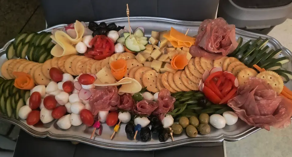 Long plateau apéritif : crackers, mozzarella, tomates cerises, olives, fromages, crudités et roses de jambon