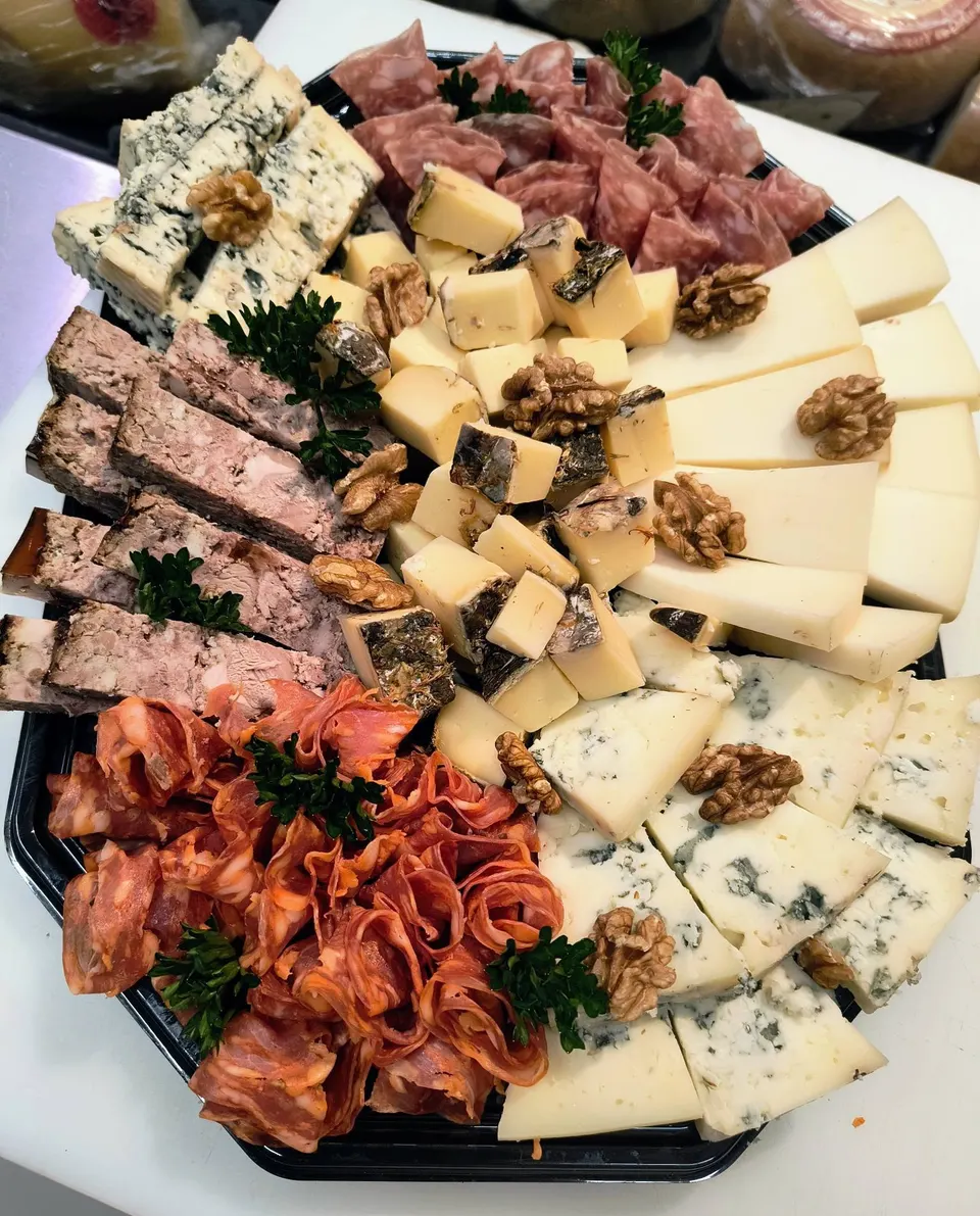 Plateau de fromages (bleus, tomme, pâte dure), terrine, chorizo et saucisson, décoré de noix et de persil