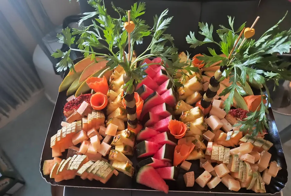 Grand plateau de fruits, melon, pastèque et fromages en dés, décoré de palmiers en carotte et persil