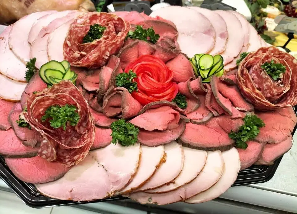Viandes froides tranchées décorées de roses de saucisson, rose de tomate et persil