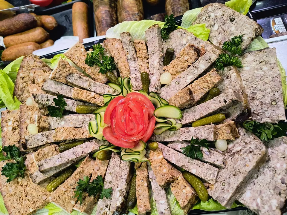 Terrines et pâtés tranchés en soleil autour d’une rose de tomate, cornichons et persil